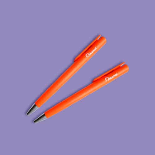 Dos bolígrafos naranja con logotipo Akamai impreso en blanco.